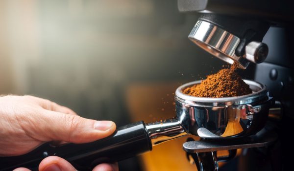 ground coffee pouring into a portafilter with a grinder, closeup