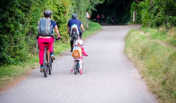 family of two adults and a child riding bikes on Camel Trail in Cornwall from Wadebridge towards Padstow, England, UK